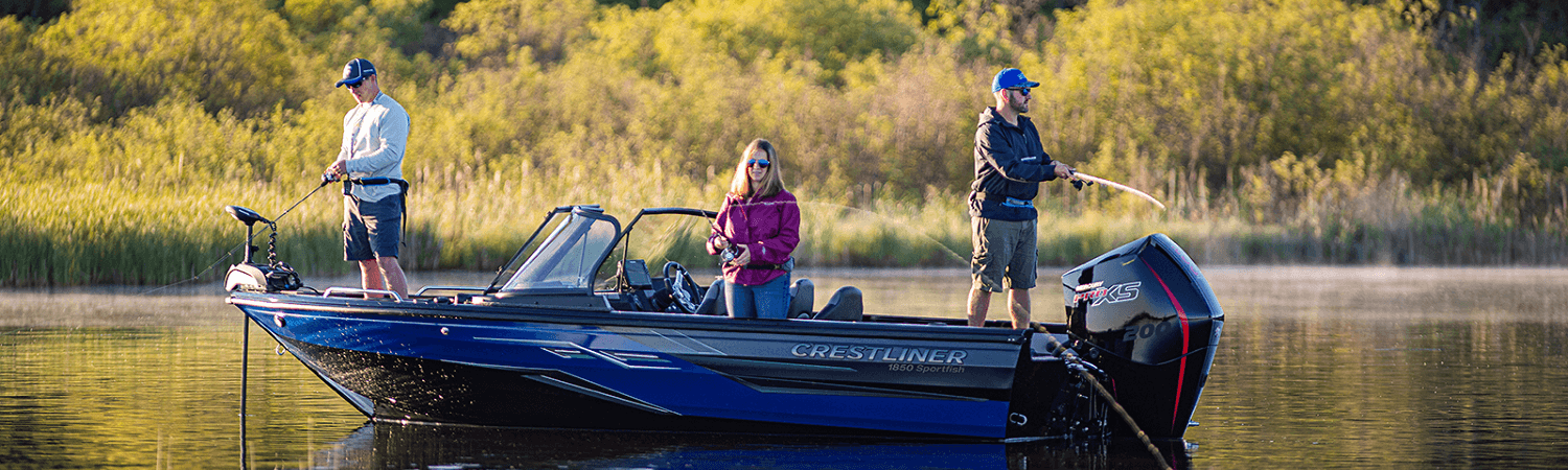 Three people fishing in a Crestliner 1850 Sportfish boat on a lake with trees and bushes in the background